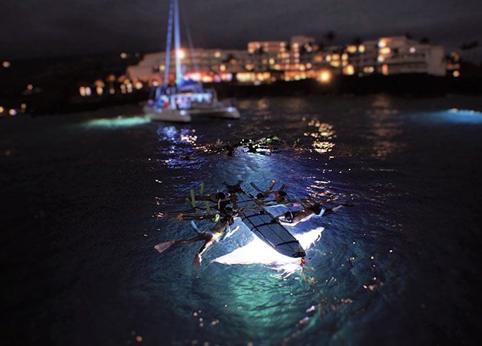 A group of people are floating in the water at night