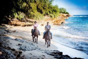 A man and a woman are riding horses on the beach.