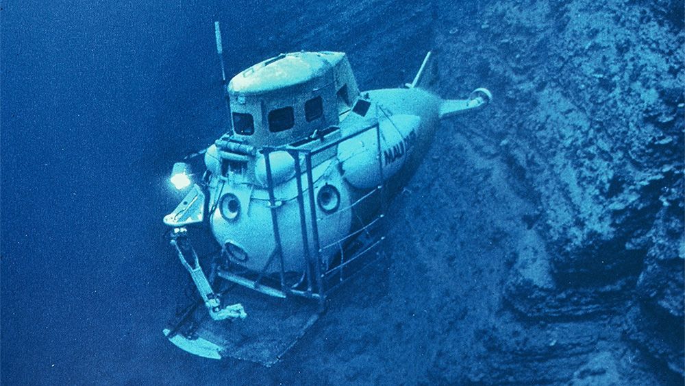 A submarine is floating on top of a coral reef in the ocean.
