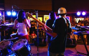A man and a woman are playing instruments on a stage in front of a crowd.
