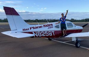 A man is standing on the wing of a small plane.