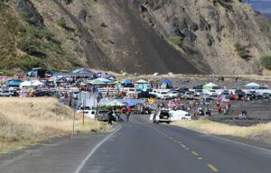 A large group of people are gathered on the side of a road.