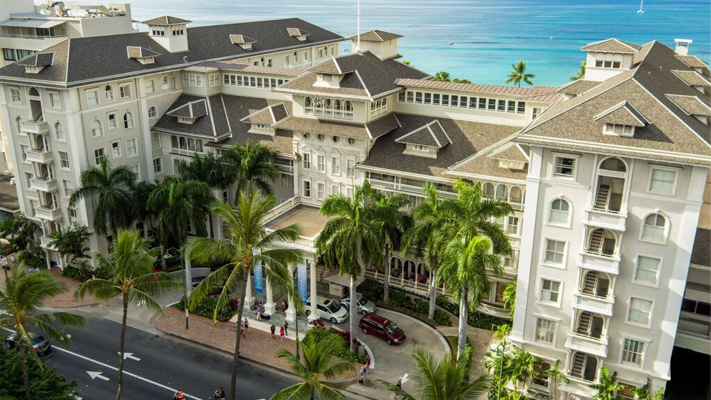 An aerial view of a hotel with palm trees in front of it