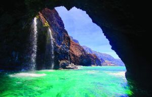 A waterfall is coming out of a cave into the ocean.