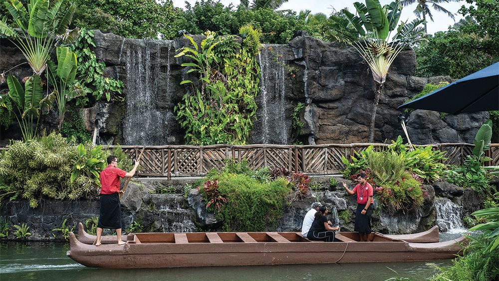 A group of people are standing on a boat in front of a waterfall.