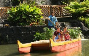 A family is riding in a red and yellow boat on a river.