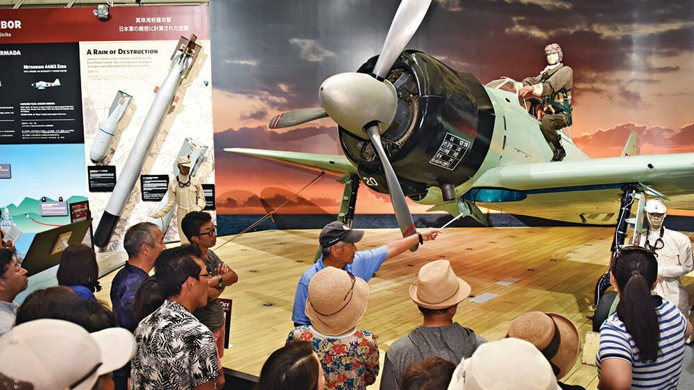 A group of people are looking at an airplane in a museum.
