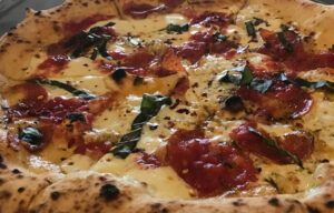 A close up of a pizza with tomatoes and cheese on a table.