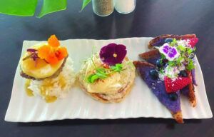 Three desserts are on a white plate on a table.