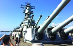 A man is taking a picture of a large battleship.