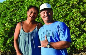 A man and a woman are standing next to each other and the man is wearing an aloha shirt.