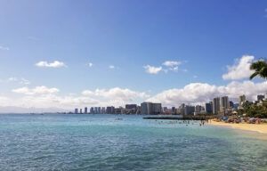 A beach with a city skyline in the background and a body of water in the foreground.