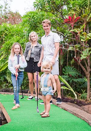 A family is playing golf together on a mini golf course.