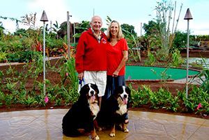 A man and a woman are standing next to two dogs.