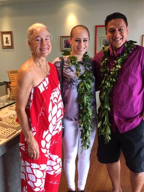 Three people posing for a picture with one wearing a lei