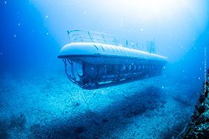 A submarine is floating in the ocean near a coral reef.