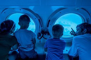 A family is looking through the windows of a submarine.