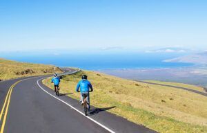 Two people are riding bicycles down a curvy road.