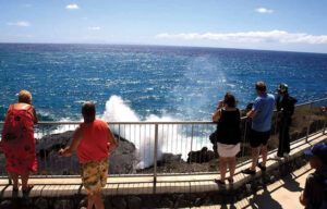 A group of people are standing on a ledge overlooking the ocean.
