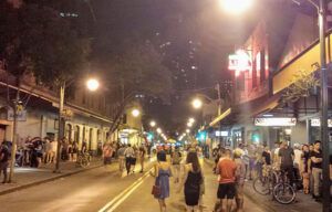 A crowd of people are walking down a city street at night.