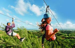 A man and a woman are riding a zip line over a forest.