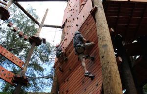 A group of people are climbing up a wooden wall.