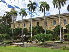 A large stone building with palm trees in front of it.