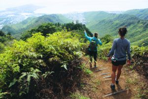 Two women are hiking on a trail in the mountains.