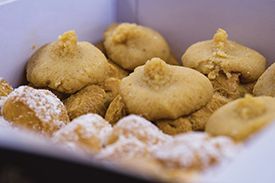 A close up of a box of cookies with powdered sugar on top.