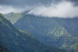 A view of a mountain range covered in trees and clouds.