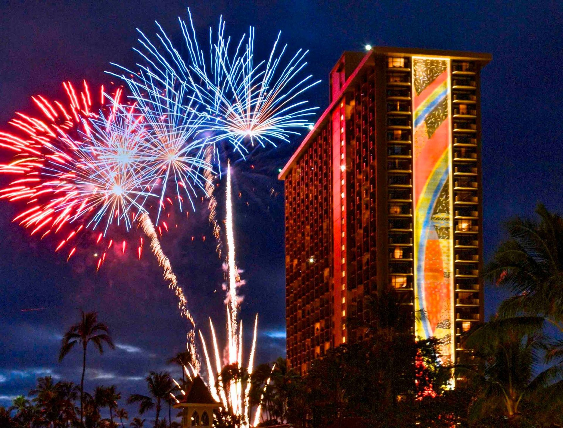 Fireworks are displayed in front of a tall building