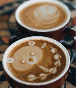 Two cups of coffee with latte art on a table.