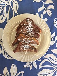 A plate of french toast with powdered sugar on a table.