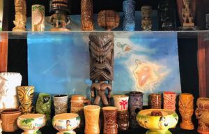 A display case filled with a variety of tiki mugs.