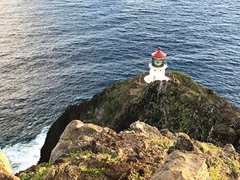 A lighthouse is sitting on top of a rocky cliff overlooking the ocean.