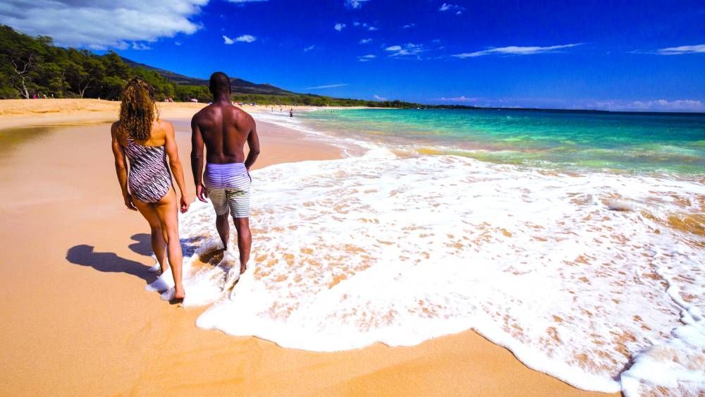 A man and a woman are walking on a beach.