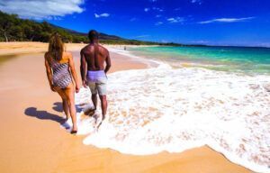 A man and a woman are walking on the beach.