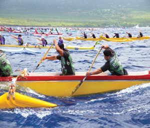 A group of people are rowing boats in the ocean.