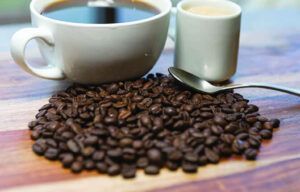 A cup of coffee is sitting on top of a pile of coffee beans.