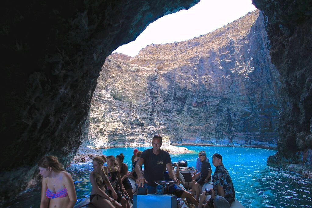 A group of people are sitting on a boat in a cave in the ocean.