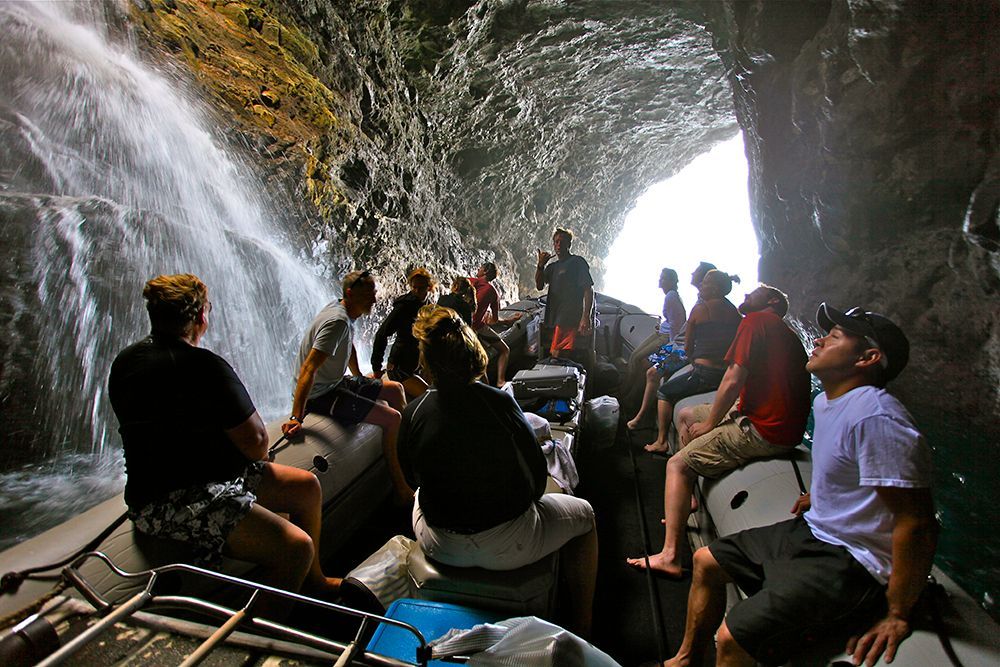 A group of people in a boat looking at a waterfall