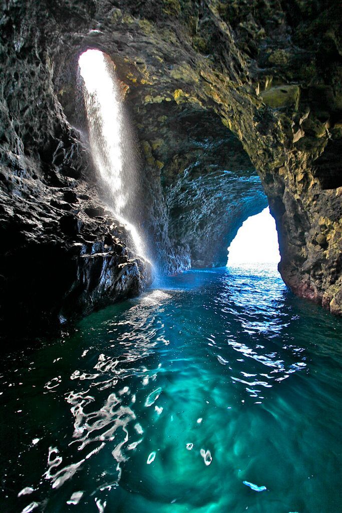 A waterfall is coming out of a cave in the ocean