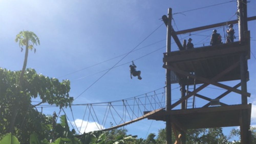 A person is flying through the air on a ropes course.