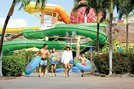 A family is walking in front of a water slide at a water park.