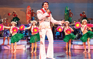 A man in a hawaiian outfit is singing into a microphone on a stage