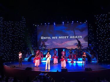 A group of people on a stage with a screen that says until we meet again