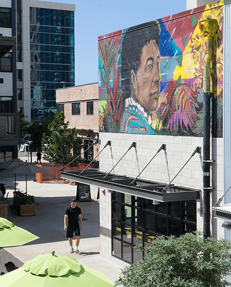 A man is walking in front of a building with a mural on it