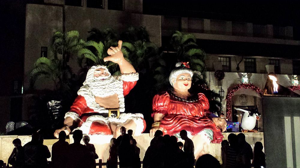 A group of people standing in front of a statue of santa and mrs claus