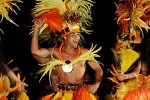 A man in a colorful costume is dancing in the dark.