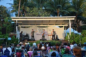 A group of people are sitting in chairs watching a band perform on a stage.
